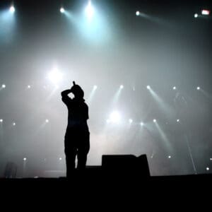 A silhouette of a person using the Quisq Neque Porro on stage, illuminated by bright spotlights in the background.