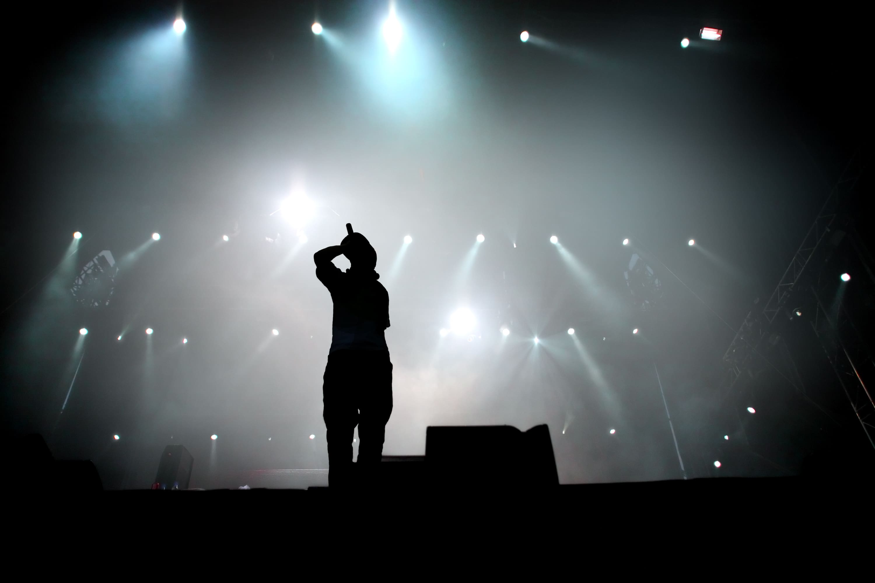 A silhouette of a person using the Quisq Neque Porro on stage, illuminated by bright spotlights in the background.