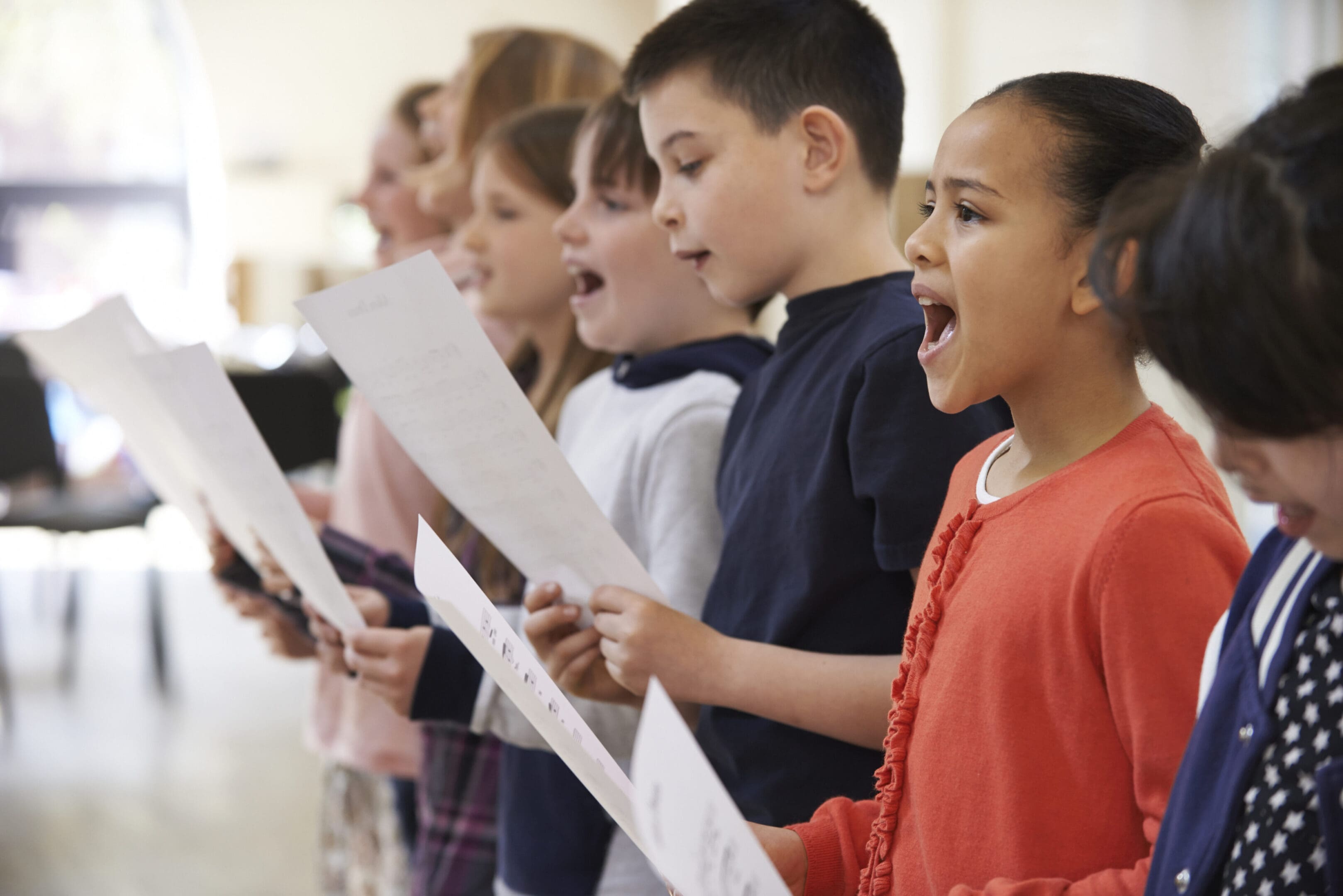 A group of children singing in front of an audience.